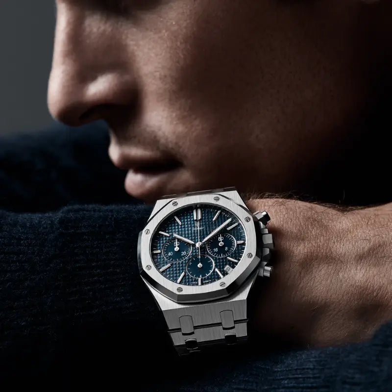 Close-up of VEXO Kings Oak Ocean Chronograph watch on a man's wrist, showcasing the deep blue textured dial, brushed stainless steel case, and integrated bracelet in a thoughtful, elegant pose