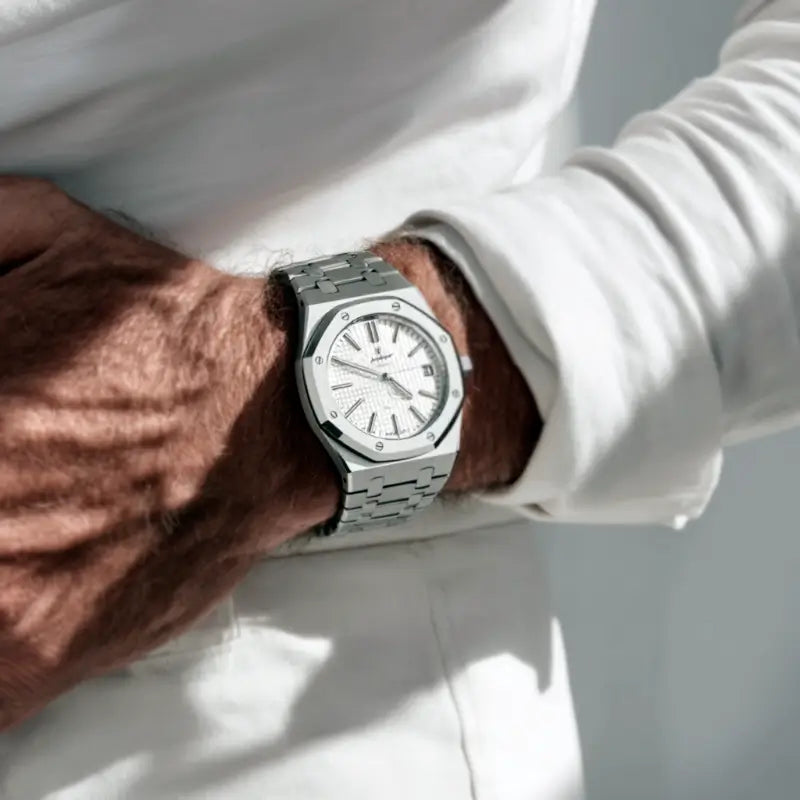 Wrist shot of the VEXO Kings Oak Ice watch styled with a white long sleeve, featuring stainless steel bracelet and white waffle-textured dial with luminous markers